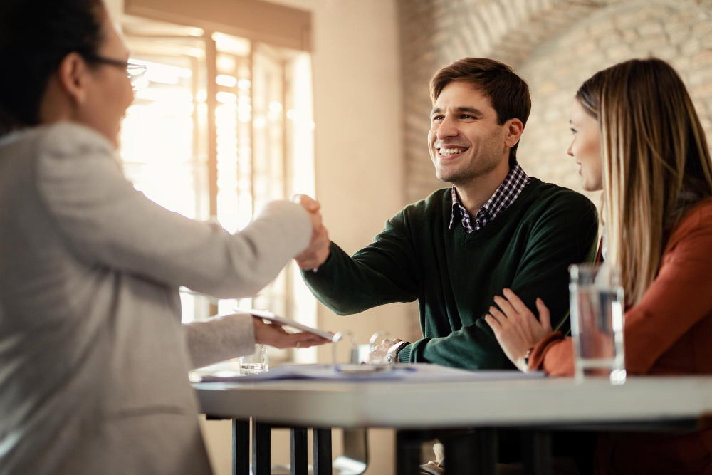 pareja-feliz-dandose-mano-asesor-financiero-reunion-oficina-foco-hombre